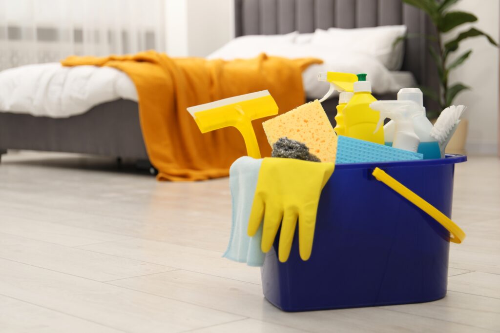 Reinigungsmittel die beim Facility Management genutzt werden in einem Eimer vor einem Bett